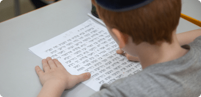 Um aluno lendo uma folha com textos em hebraico.