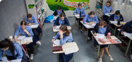 Várias alunas concentradas na tarefa em uma sala de aula.