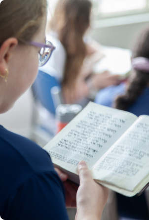Uma aluna lendo um livro hebraico.